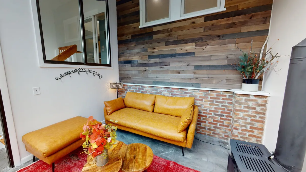 A warm, inviting living area with a yellow leather couch, wooden coffee table, brick wall, decorative plant, and a red area rug. The space conveys comfort and togetherness, inviting families to gather around for relaxation or storytelling.