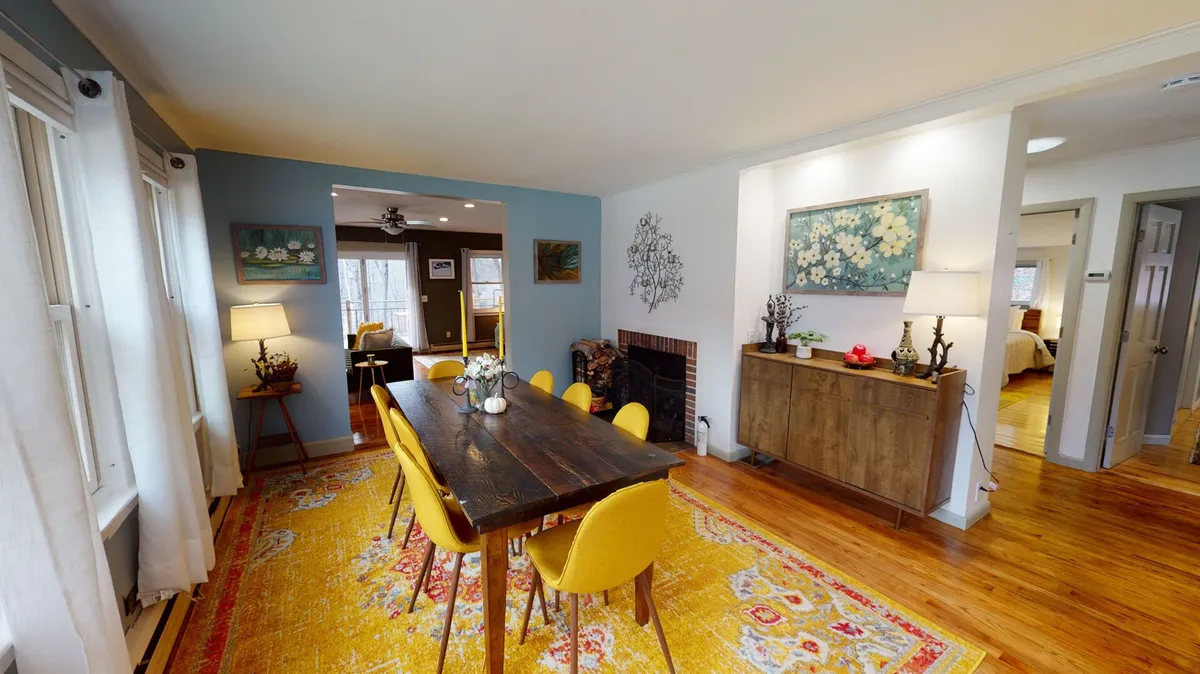 The hero image showcases a bright, inviting dining area with a large table surrounded by cheerful yellow chairs, a cozy rug, and tasteful wall art. The warm lighting and spacious layout create the perfect setting for family dinners, friendly gatherings, and memorable game nights.