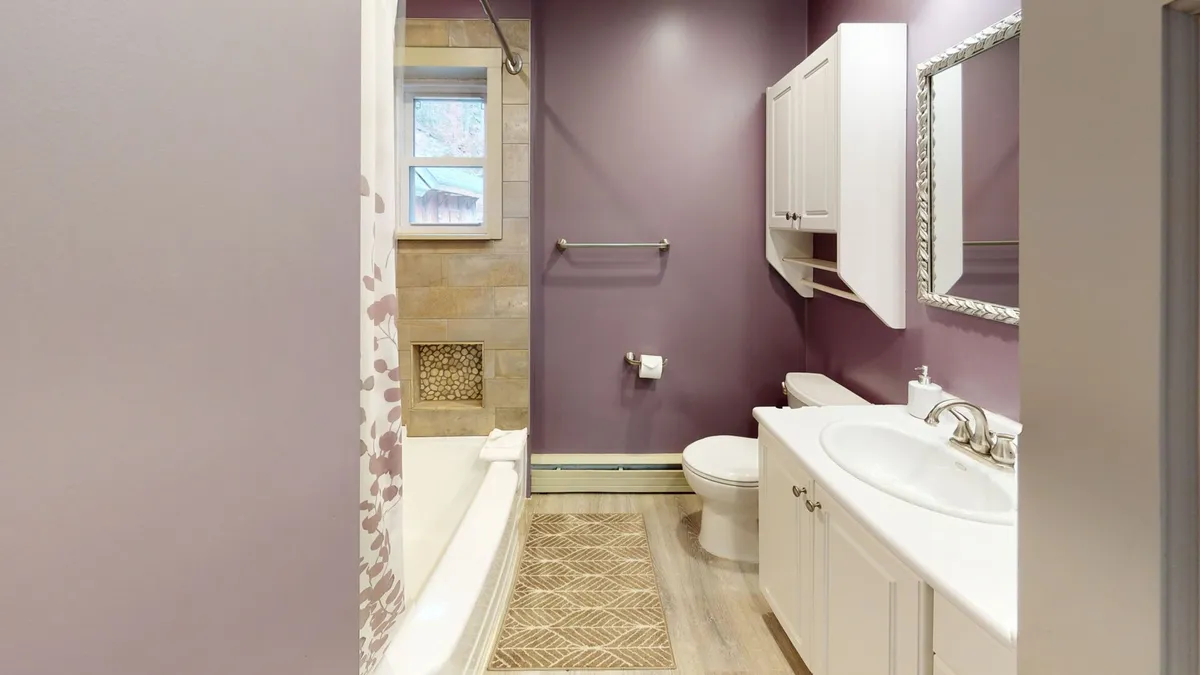 A modern and stylish bathroom with a deep bathtub, vanity with sink and mirror, and soft lighting. The atmosphere is calm, perfect for relaxing or morning routines.